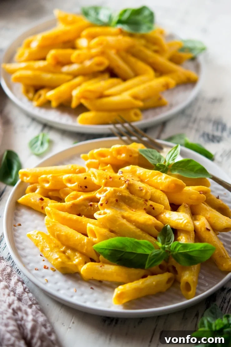 Butternut Squash Pasta Close Up A close-up shot of creamy butternut squash pasta on a white plate, garnished with fresh basil leaves, highlighting the rich texture of the sauce.