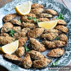A cropped square image of mussels topped with golden breadcrumbs on a elegant serving platter, ready to be eaten.