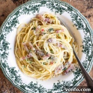 A close up cropped image on Spaghetti alla Molisana with pancetta, onion and chilli in a green patterned bowl.