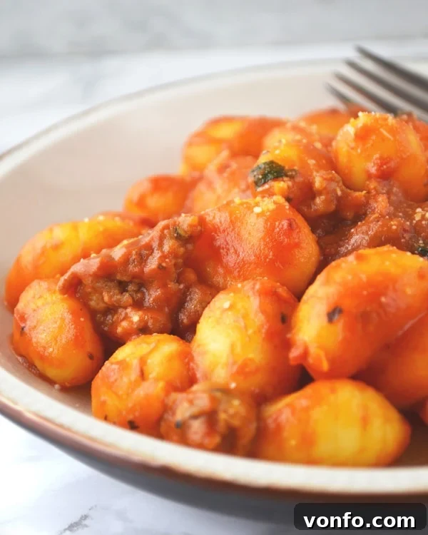 A bowl of freshly cooked gnocchi being tossed with the homemade spicy 'Nduja tomato sauce, ensuring every piece is coated.