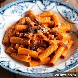 A close up of pasta alla zozzona in a blue and white bowl, ready to serve.