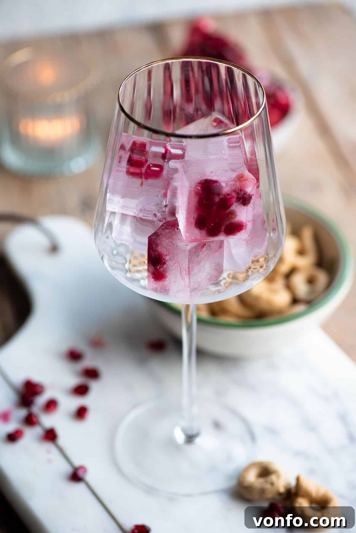 Pomegranate Spritzers 3 A close-up of an elegant wine glass with a luxurious gold rim, filled with homemade pomegranate ice cubes, showcasing their festive and vibrant appearance.