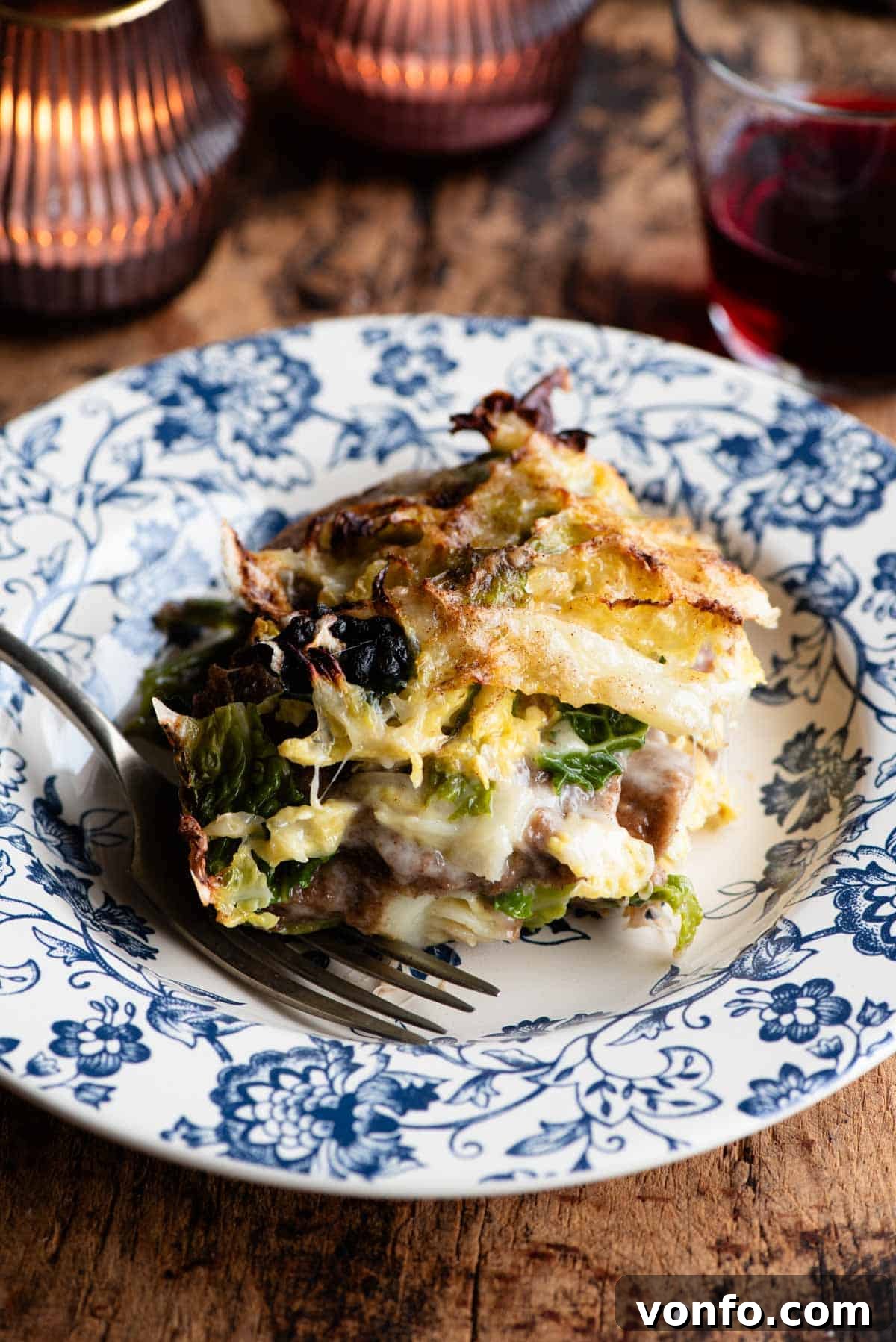 A generous slice of rustic Italian casserole, Zuppa alla Valpellinese, served on a beautiful blue ceramic plate, showcasing its golden cheese topping and layered interior.