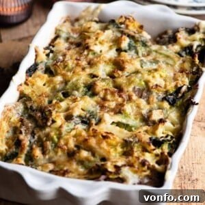 A close-up cropped image of a golden-brown cheese and cabbage casserole in a baking dish, freshly out of the oven.