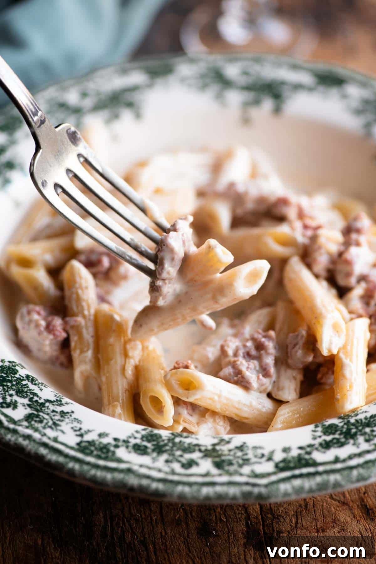 Norcia's Creamy Truffle Sausage Pasta 6 A close up of a fork picking up a bite of creamy sausage pasta.