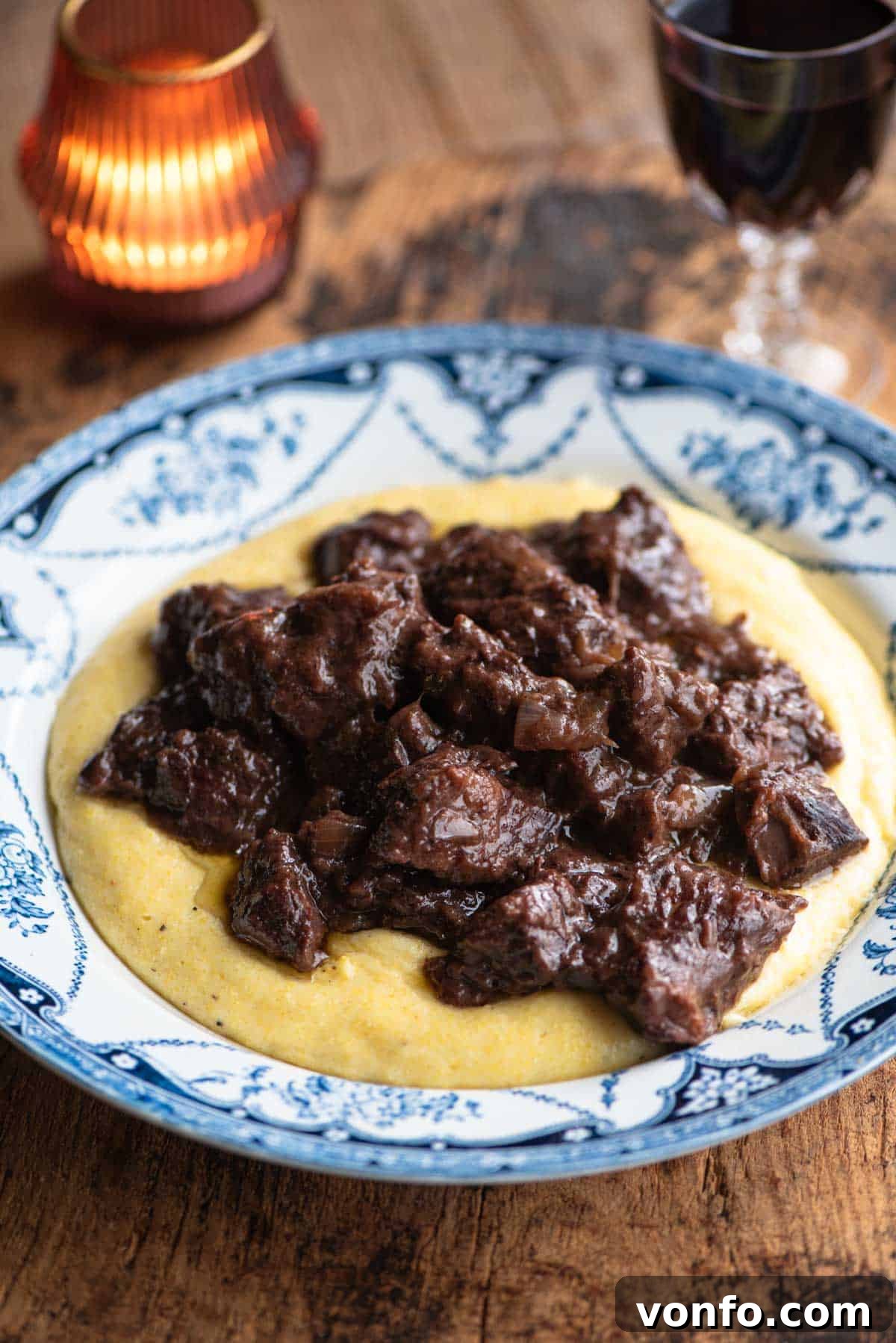Carbonade Valdostana: Hearty Red Wine Beef Stew with Aromatic Spices 2 Carbonade beef stew served on top of polenta in a blue and white bowl, ready to be enjoyed.