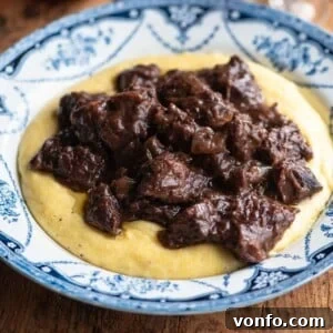 A close up cropped image of Carbonade beef stew on top of polenta, ready to be served.