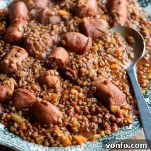 A cropped square image of Italian sausages and lentils on a serving plate, highlighting the deliciousness of the dish.