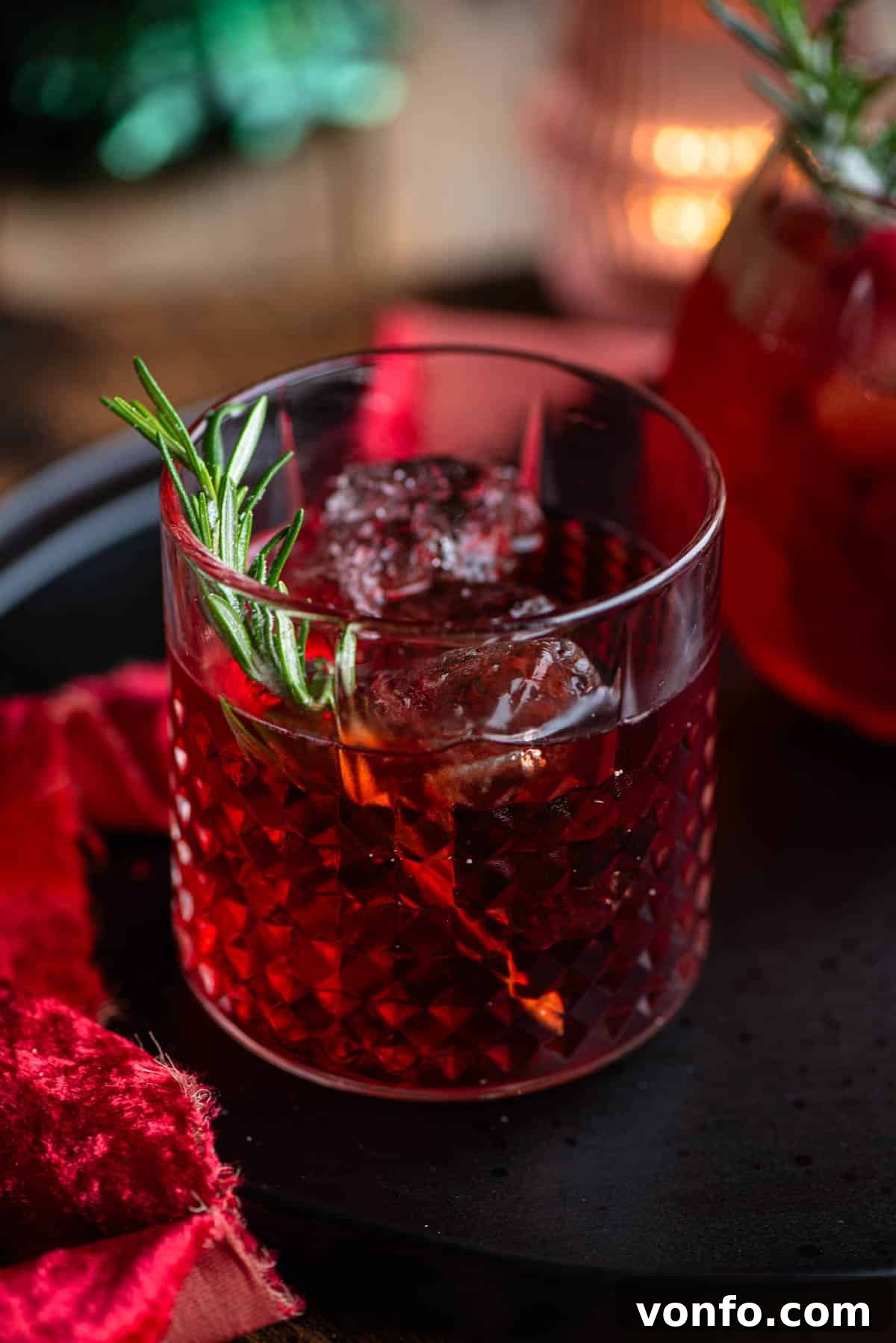 A close-up of The Sbagliato Rosso cocktail in a glass with a sprig of rosemary, emphasizing its rich color and inviting texture.