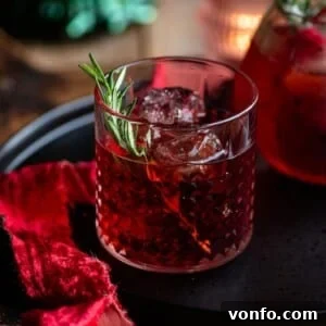 A close-up cropped image of a red Italian cocktail in a short glass with a rosemary sprig, ready to be enjoyed.