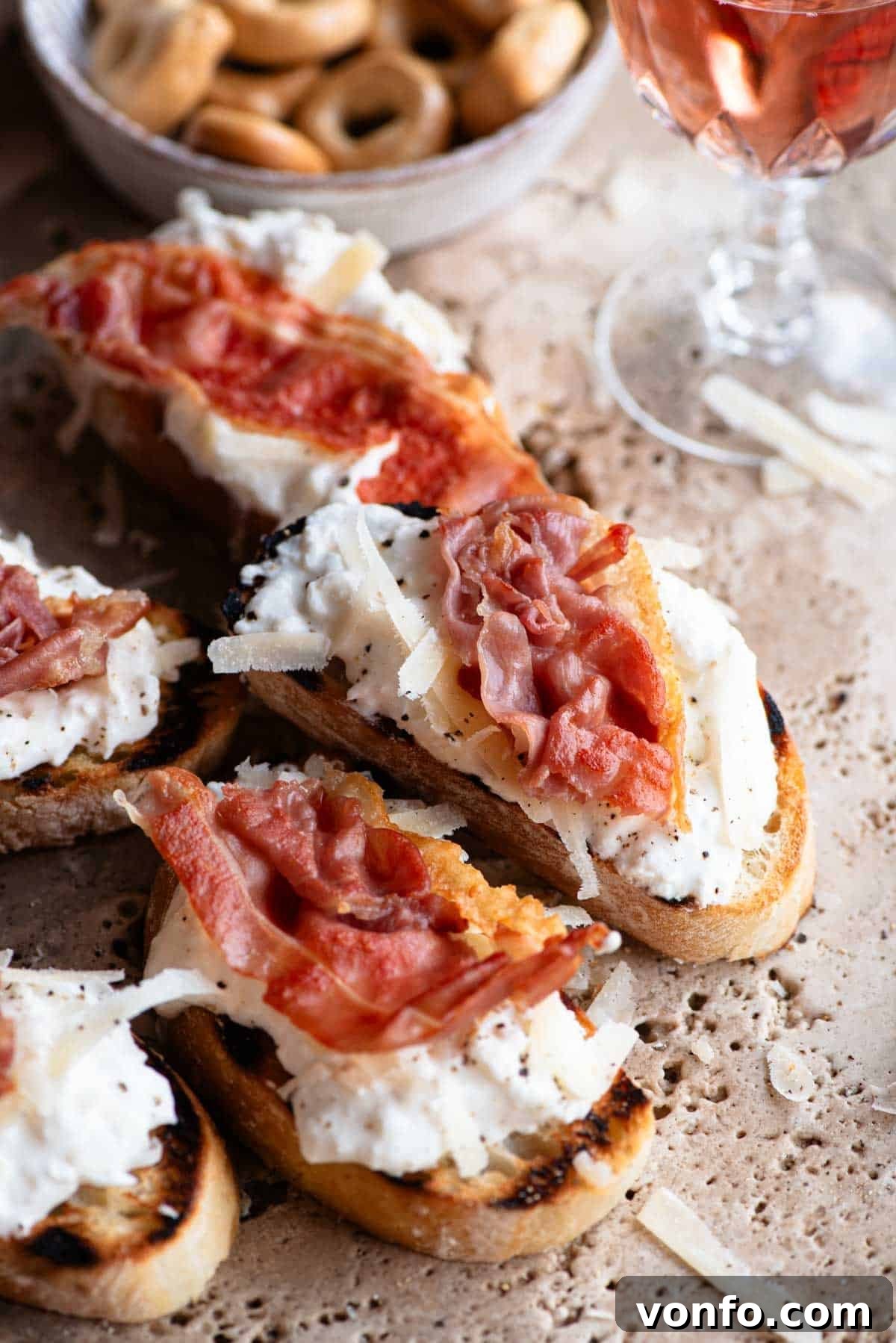 A mesmerizing close-up of a single crostini slice, artfully adorned with a dollop of creamy burrata, generous shavings of golden Parmigiano Reggiano, and perfectly crispy, rich prosciutto.