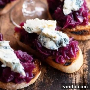 A close up cropped image of red onion crostini topped with gorgonzola cheese, perfectly showcasing the caramelized chutney and crumbly cheese.