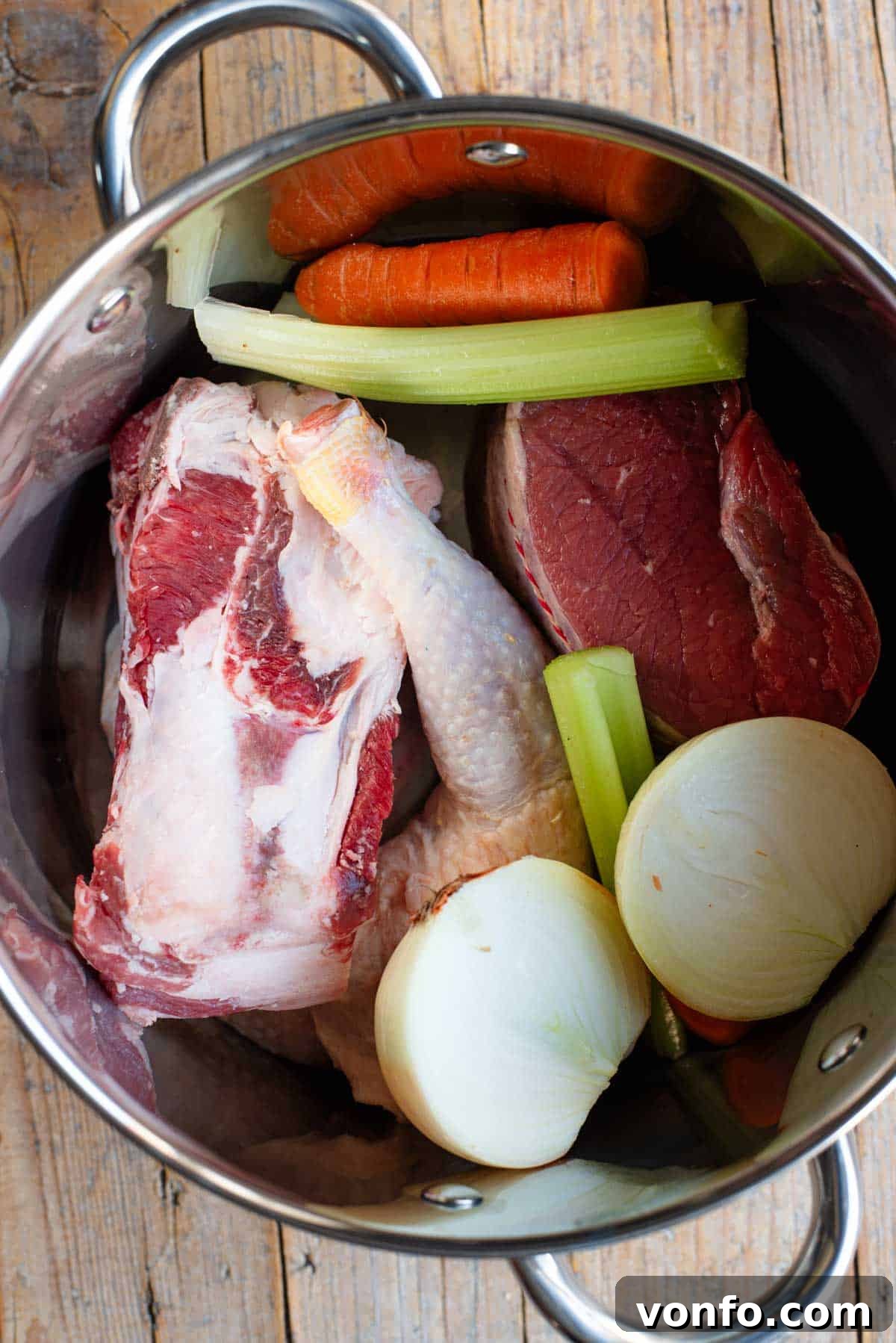 Classic Italian Meat Broth 2 A large stockpot filled with various cuts of meat and fresh root vegetables simmering to create a rich Italian meat broth.