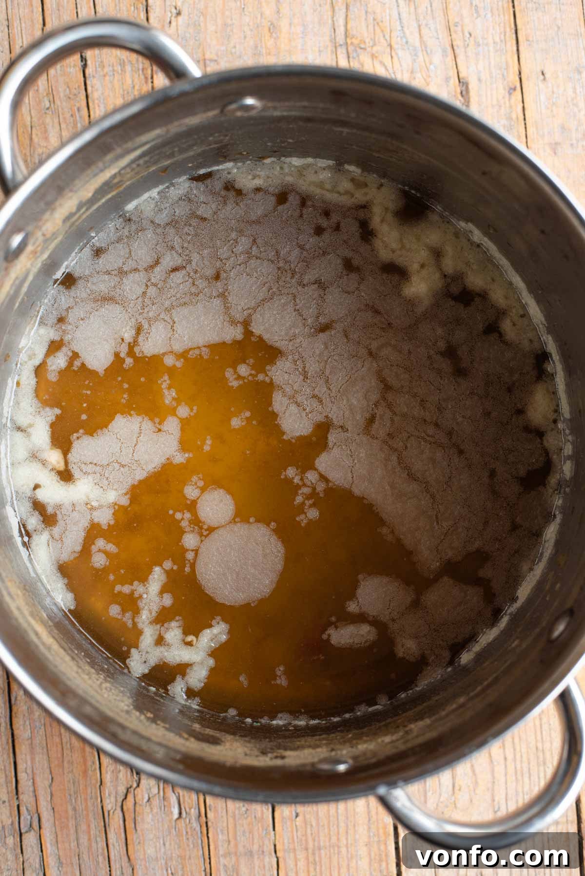 Classic Italian Meat Broth 4 A close-up photograph showing a distinct layer of solidified fat floating on top of cooled Italian meat broth in a bowl.