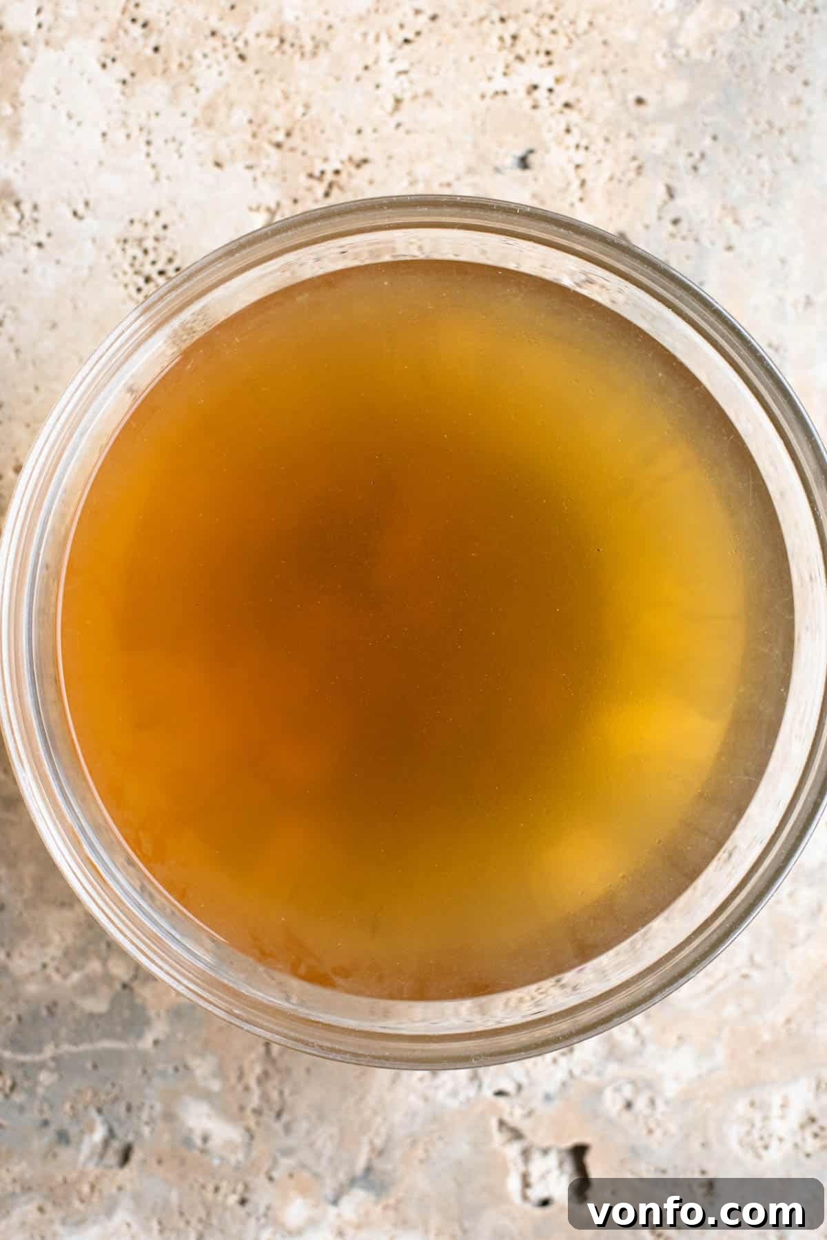 Classic Italian Meat Broth 5 A glistening, clear Italian meat broth (Brodo di Carne) served in an elegant glass bowl, ready to be used or enjoyed.