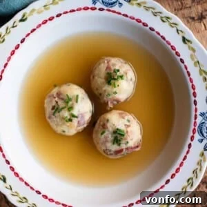 A cropped square image of Canederli dumplings in meat broth.