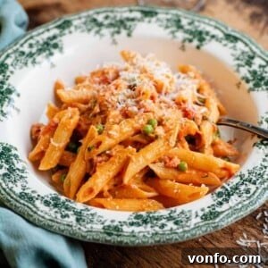 Signature Seven P Pasta 7 A cropped square image of a bowl of creamy tomato penne pasta on a wooden table.