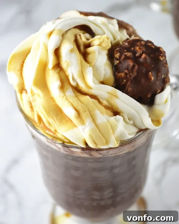 Close-up of Baileys Hot Chocolate with Maple Whipped Cream, adorned with a Ferrero Rocher, showcasing its rich texture and luxurious topping.