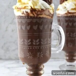 Rich and creamy Baileys Hot Chocolate topped with maple whipped cream and a Ferrero Rocher, a festive winter treat.