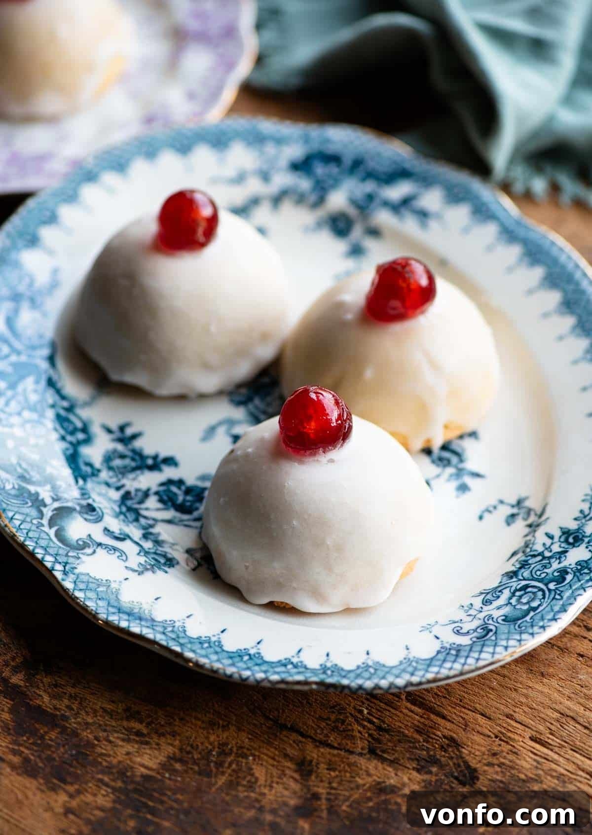 Minne di Sant'Agata: Beloved Sicilian Delicacies 2 Three Sicilian pastries sitting on a blue patterned plate, the pastries are dome shaped with white icing and a cherry on top.