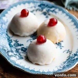 A cropped square image of three Sicilian pastries on a blue plate topped with white icing and a cherry.