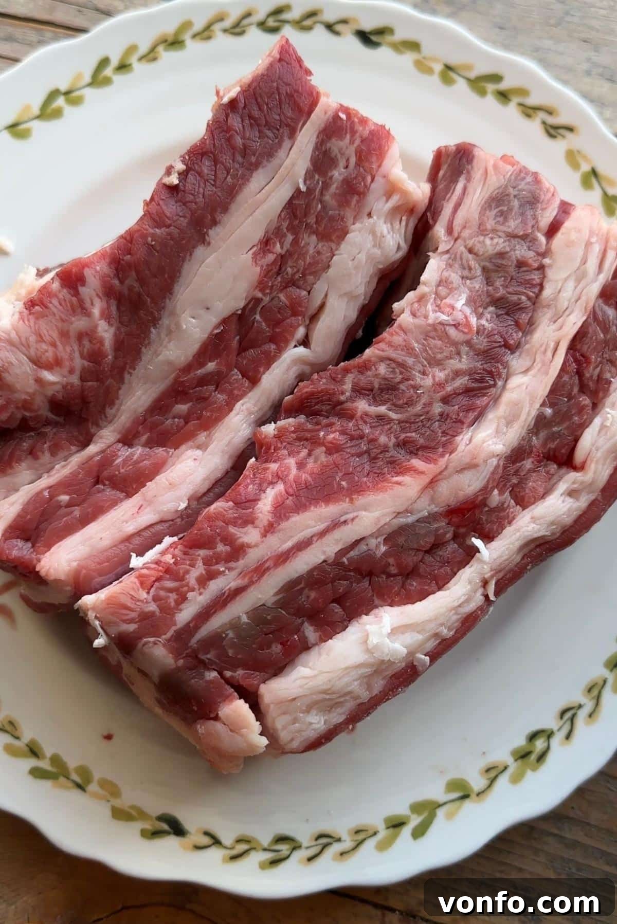 A close up of two beef short ribs on a plate with the lifter muscle attached, showcasing typical UK cuts.