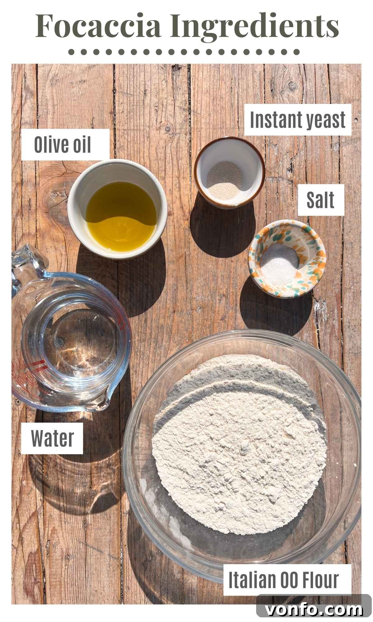 Snooze Button Overnight Focaccia 3 All the ingredients needed to make a focaccia laid out on a rustic wooden surface.