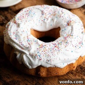 Ciaramicola: Umbria's Vibrant Easter Bundt 8 A close-up of a beautifully decorated Ciaramicola Italian Easter bundt cake, showcasing its vibrant pink interior visible through a cut slice, adorned with fluffy white meringue and colorful sprinkles.