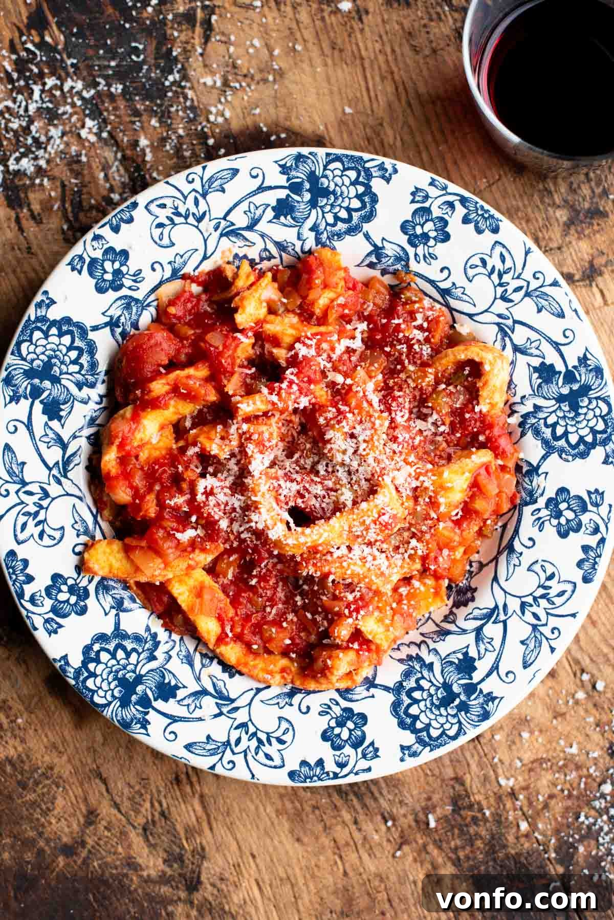 Hearty Faux Tripe Ragù 2 Trippa Finta, an Italian omelette in tomato sauce, served in a beautiful blue and white bowl on a rustic wooden surface.