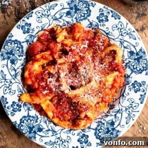 A vibrant bowl of Trippa Finta, an Italian omelette in tomato sauce, resting on a wooden surface.