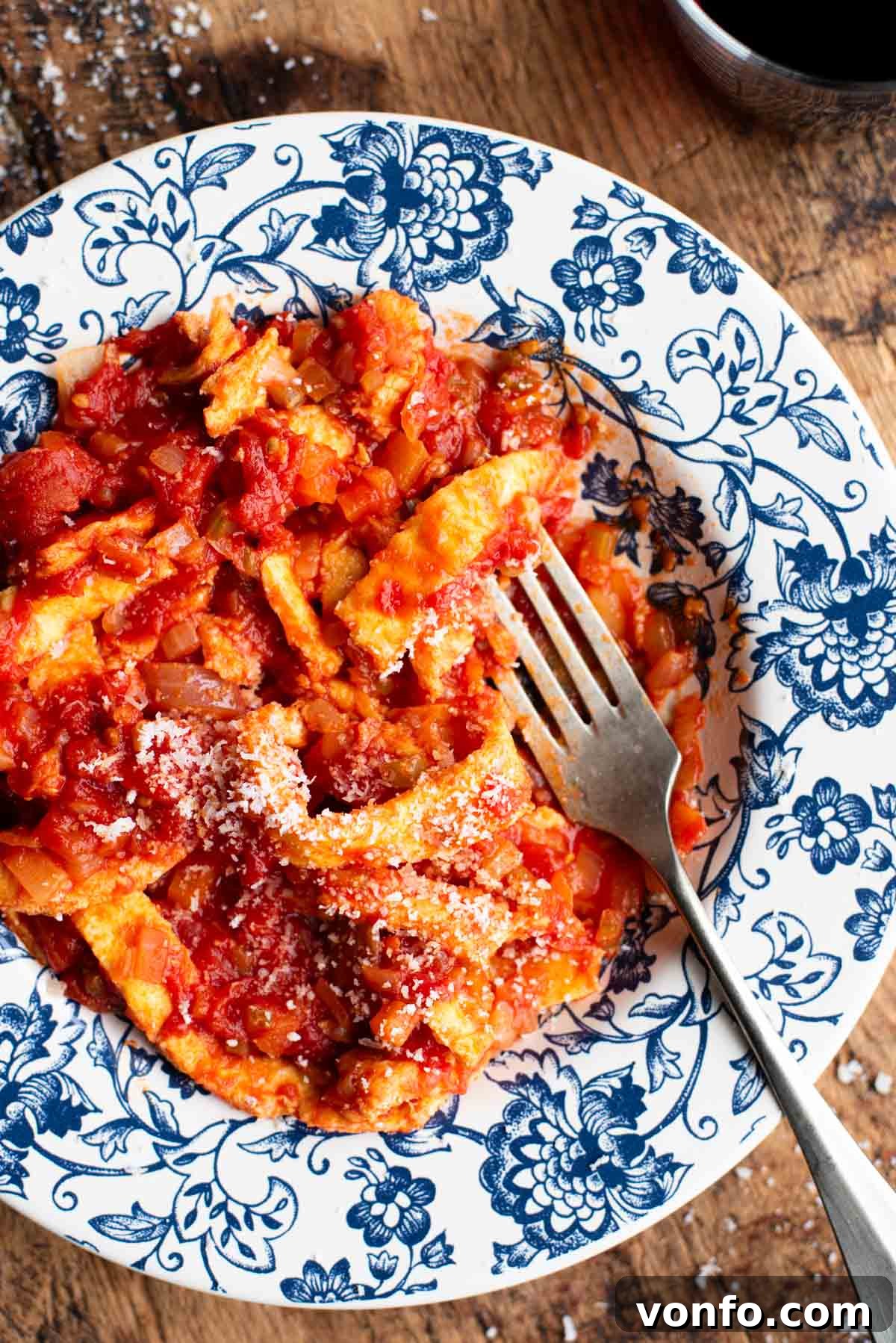 Hearty Faux Tripe Ragù 7 A close-up shot of a fork digging into a bowl of Italian Trippa Finta (omelette in tomato sauce), highlighting the texture of the 'fake tripe' and the rich sauce.
