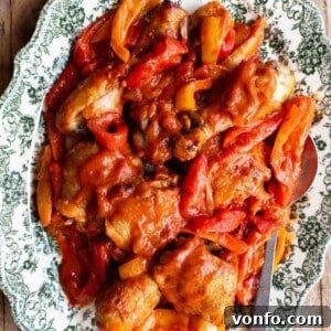 A close up of chicken and peppers on a green and white servings plate, beautifully plated.