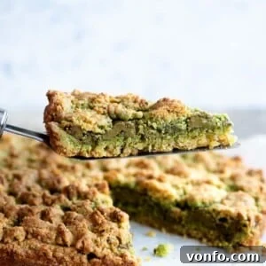 Rustic Italian Pistachio Crumb Cake 5 A close-up shot of a slice of pistachio crumb cake being held on a cake server, highlighting the crumbly texture and filling.
