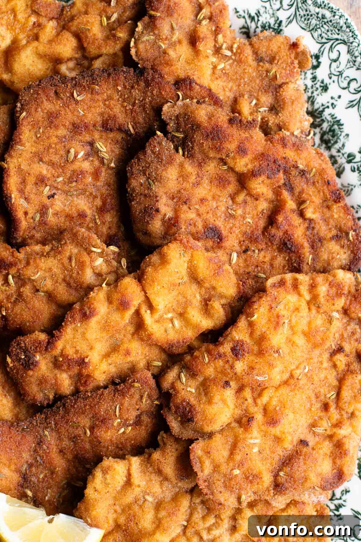 Fennel-Crusted Pork Tenderloin 7 A close-up shot of a single, perfectly golden-brown breaded pork fillet, highlighting the crispy fennel seed crust, resting on a white plate.