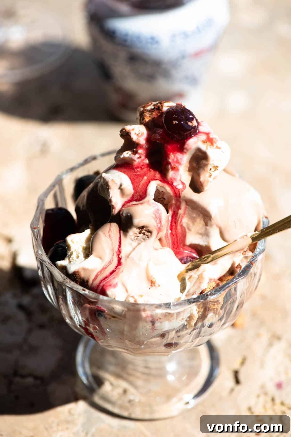 A close up of an Italian ice cream sundae melting in a glass bowl with a amarena cherries.