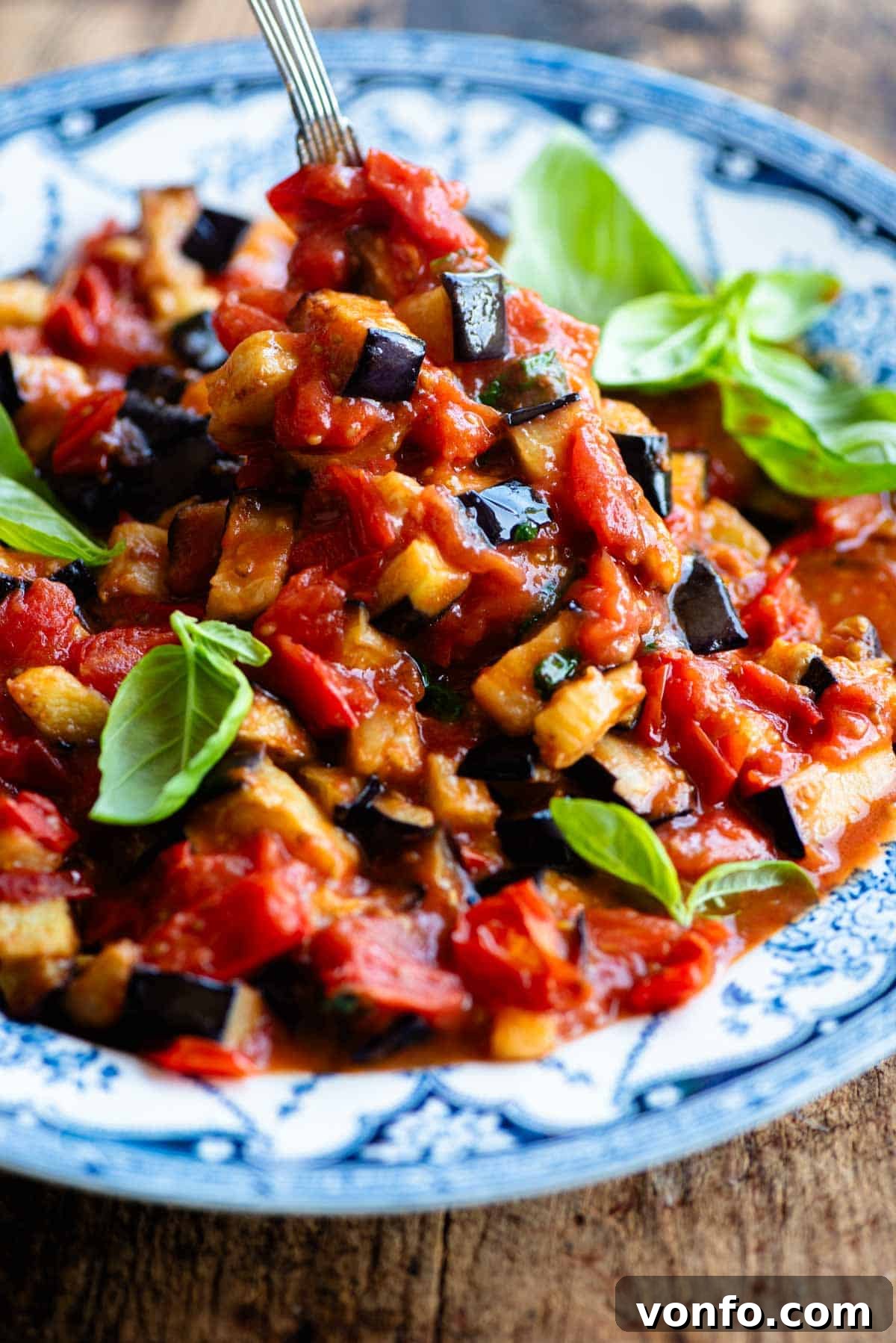 Golden Fried Eggplant Simmered in Rustic Tomato Sauce 4 A close-up of beautifully fried eggplant pieces glistening in a rich cherry tomato and basil sauce, served in a rustic bowl.