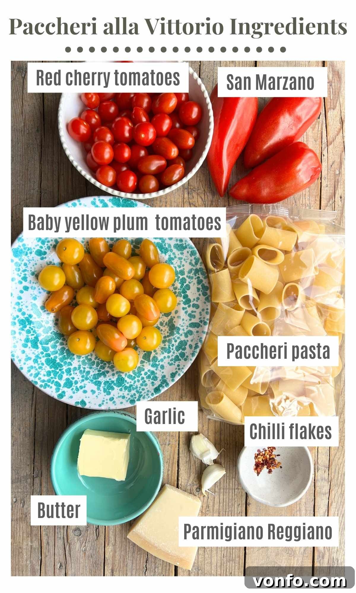 All the ingredients needed to make Paccheri alla Vittorio laid out on a wooden board, including fresh plum tomatoes, cherry tomatoes, butter, Parmigiano Reggiano, garlic, chilli flakes, and paccheri pasta.