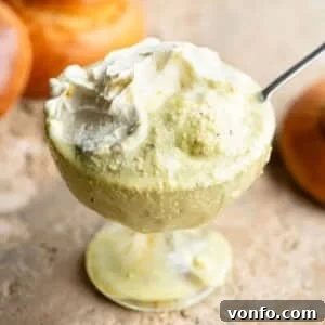 A close up of luxurious pistachio granita in a clear glass serving bowl, garnished with a generous swirl of fresh whipped cream.