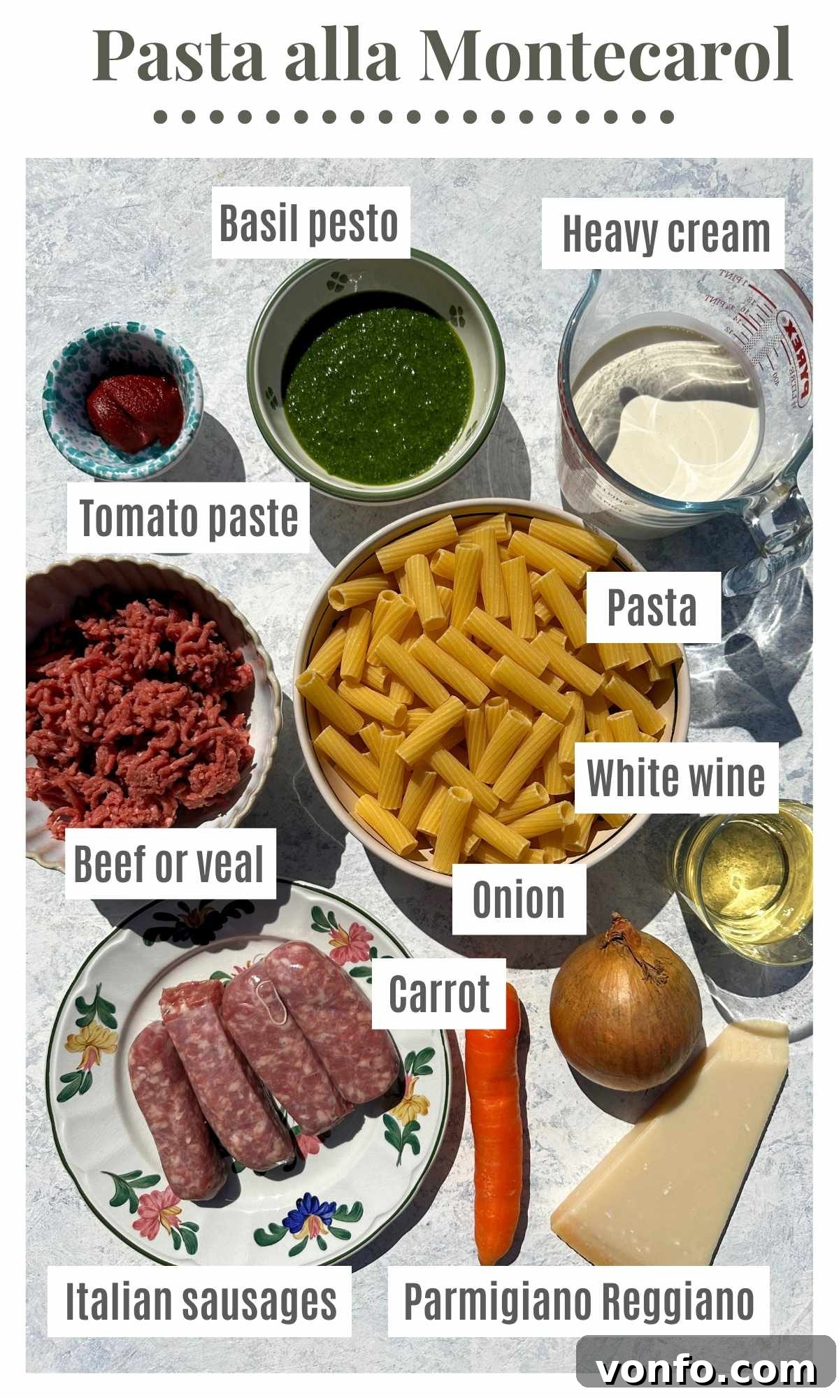 An overhead shot of all the ingredients needed to make Pasta alla Montecarlo; pesto, heavy cream, tomato paste, pasta, sausages, beef, carrot, onion, Parmesan and white wine.
