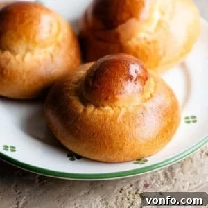 A close-up of a perfectly baked Sicilian brioche bun on a plate, beautifully adorned with white and green floral patterns.