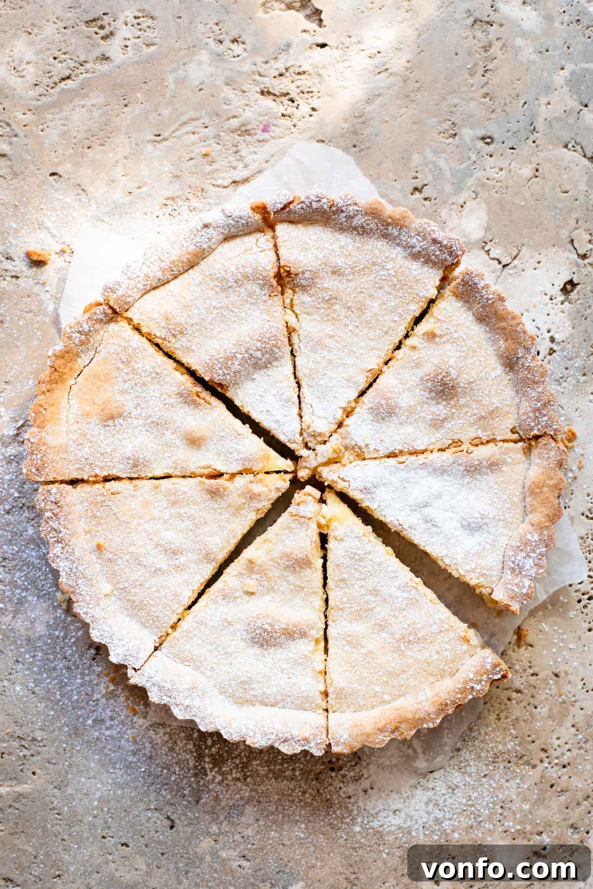 A beautifully baked Crostata Ricotta e Visciole, cut into 8 perfect slices and generously dusted with powdered sugar, resting elegantly on a pristine travertine surface.
