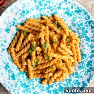 A cropped close up of tuna pasta sauce with gemelli pasta in a blue and white speckled bowl.