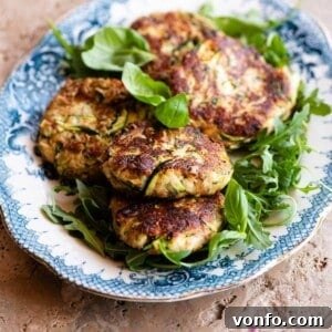A cropped image showing several freshly cooked zucchini patties on a blue and white serving plate.