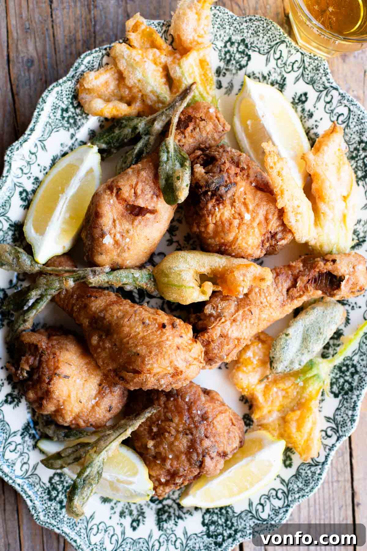 Rustic Tuscan Fried Chicken 2 A serving platter showcasing golden-brown Italian fried chicken alongside beautifully fried zucchini blossoms and fragrant sage leaves, inviting a delightful culinary experience.