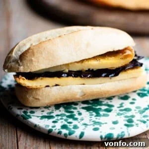 A close up of a roll filled with a chickpea flatbread and marinated eggplant.