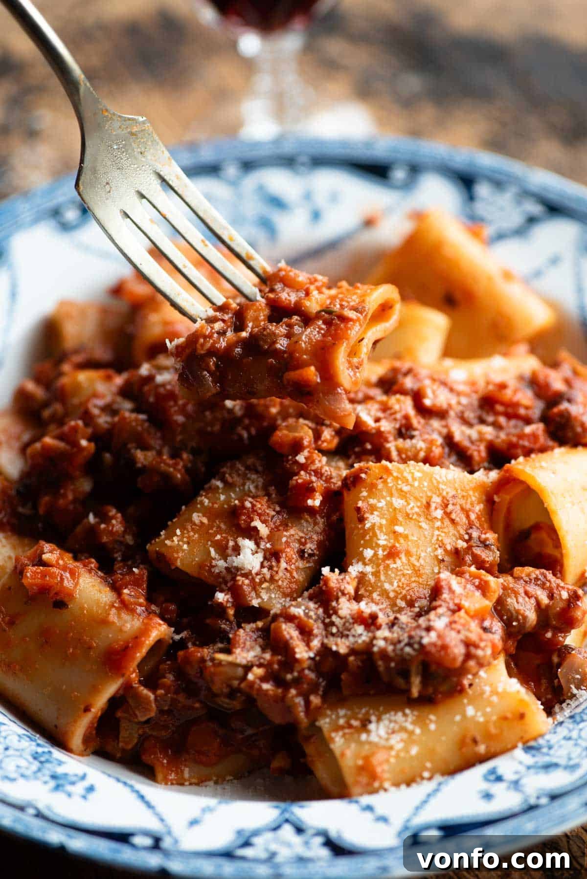 Piedmontese Hazelnut Ragu: A Rustic Italian Delight 6 A close-up shot of a fork lifting a piece of paccheri pasta generously coated with hazelnut ragu, poised above a serving bowl, highlighting the delicious texture of the sauce.