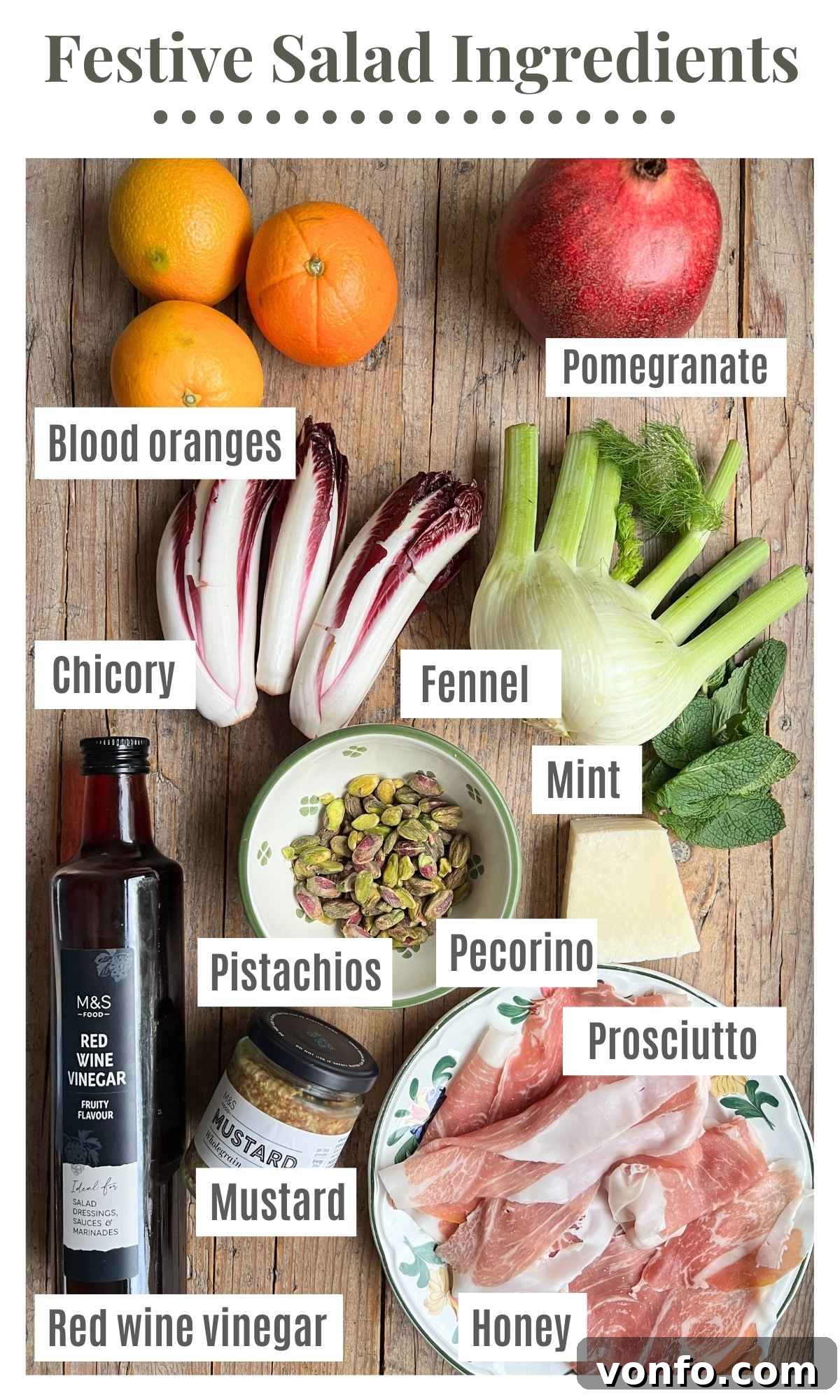 All the ingredients for a festive blood orange salad laying on a rustic wooden surface. The labels read: blood oranges, pomegranate, fennel, chicory, red wine vinegar, mustard, mint, honey, prosciutto, pistachios, and pecorino.