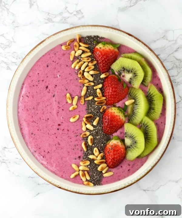 Berry Banana Smoothie Bowl topped with kiwi and strawberries on a wooden surface