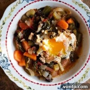 A close up cropped image of Acquacotta soup topped with a poached egg in a bowl, highlighting its inviting presentation.