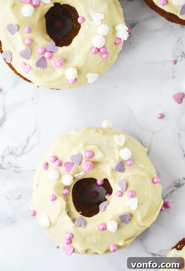 Stack of carrot cake doughnuts with maple frosting, garnished with colorful sprinkles. www.insidetherustickitchen.com